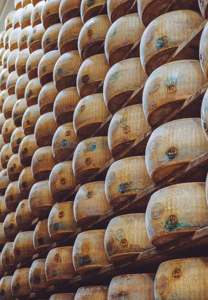 Servizi Rows of aged Parmesan wheels on wooden racks in a traditional Italian cheese factory.